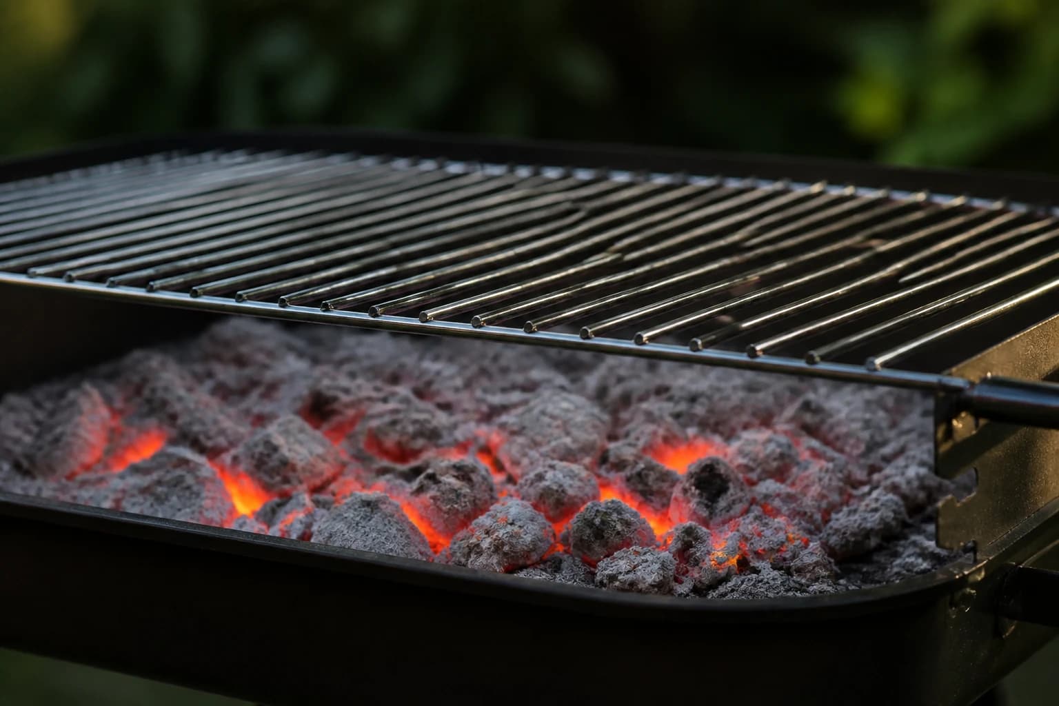 Des braises rougeoyantes couvertes d'un voile de cendre grise, surmontées d'une grille placée en hauteur, sans aucune flamme