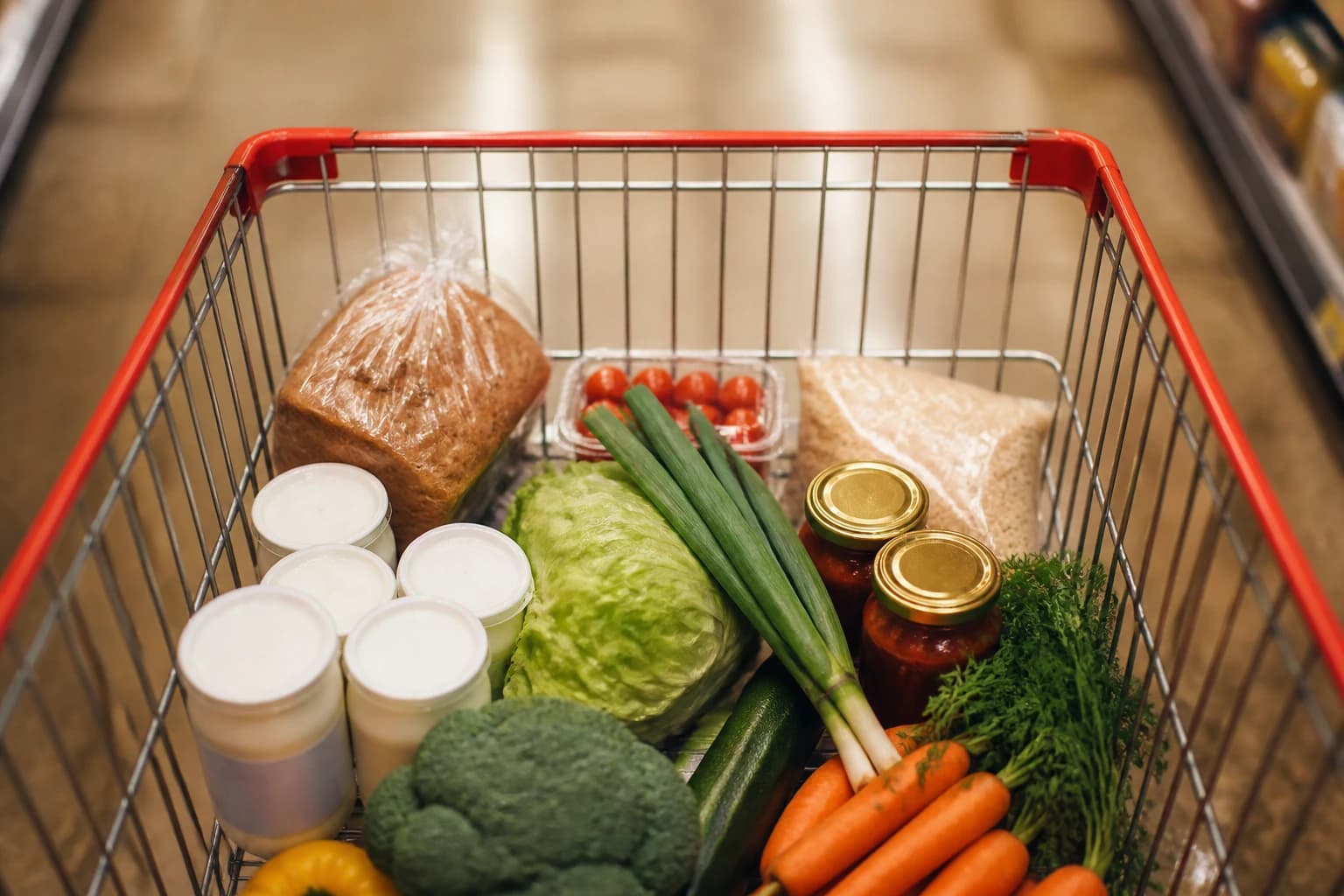 Chariot de courses de rentrée avec yaourts, sauces pour pâtes, légumes frais et pain complet